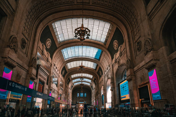 Milano Centrale - The main railway station with several people in a huge hall.