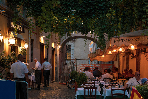 Rome, Italy - August 15 2023: Restaurant with outdoor seating at evening. Waiters serving food outside