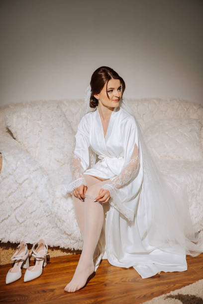 a beautiful brunette bride with a tiara in her hair is getting ready for the wedding in a beautiful robe in boudoir style. close-up wedding portrait, photo. - jewelry glamour brown hair stage makeup stock-fotos und bilder