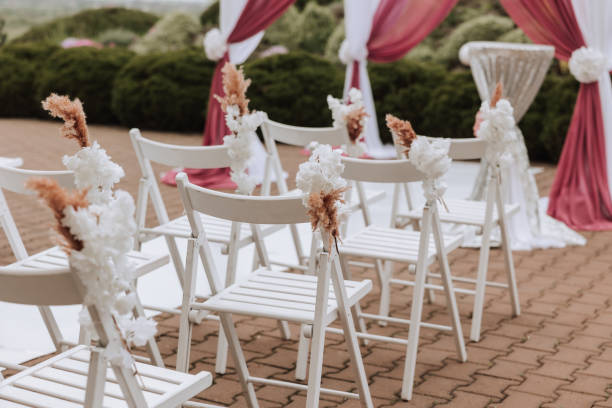 istock Wedding decor. Many white chairs and a white path. A white and pink arch decorated with flowers. Preparation for the wedding ceremony. Celebration 2103002303