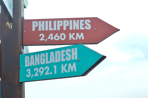 Close-up shots of directional signs pointing towards the enchanting destinations of the Philippines and Bangladesh beckon