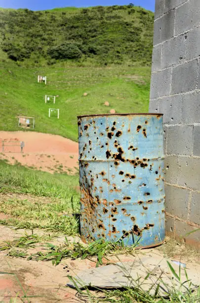 A big drum all pierced by shots at the shooting club in the field on a sunny day