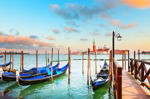 Gondolas on the Grand canal at sunset in Venice, Italy. San Giorgio Maggiore Cathedral in the background. Famous travel destination.