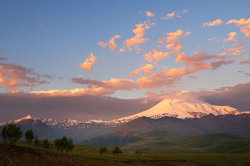 Elbrus mount with pink clouds at sunrise. View from Gil-Su valley in North Caucasus, Russia. Beautiful summer landscape.