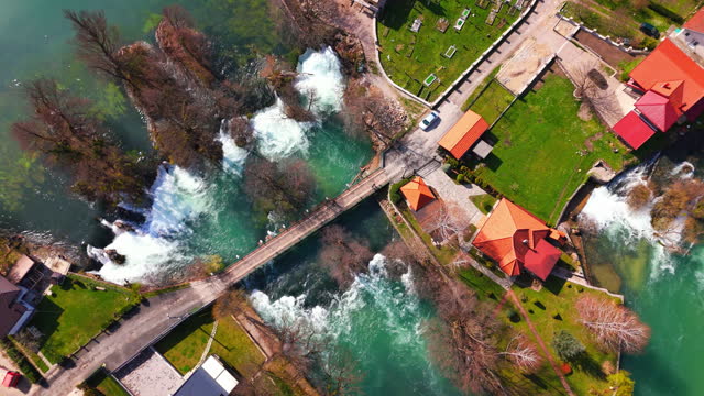 AERIAL Drone Top Down Shot of Una River Flowing Below Bridge in Small Town, Bosnia and Herzegovina