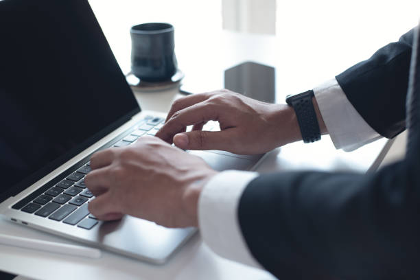 istock Businessman working on laptop computer on white table at office. Business man hands typing on laptop, online working, surfing the internet, close up 2103195948