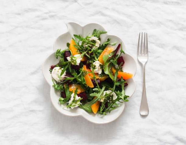 istock Delicious salad with beetroot, arugula, cheese and oranges on a light background, top view 2103206280