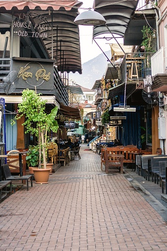 Fethiye, Turkey - December 8, 2022: Charming cobblestone alleyway with vibrant storefronts and outdoor seating in the old town.