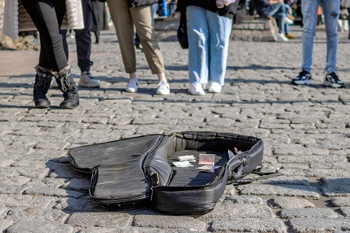 Istanbul, Turkey - December 29, 2022: Open guitar case on the street for donations with blurred people in the background.