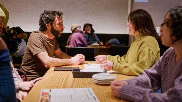 istock Skiers on Lunch Break Chatting While Friends Scan Room for a Waiter 2103322315