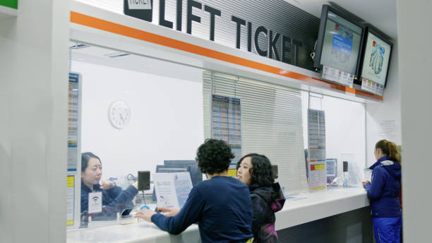 A Caucasian man and Japanese woman buying lift tickets in the lodge at a ski resort in Niseko, Japan.