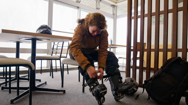 Man adjusting ski boots in icy parking lot