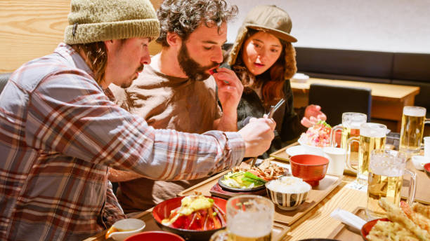 istock Three Friends Sharing a Meal inside Japanese Restaurant After Skiing Together 2103326056