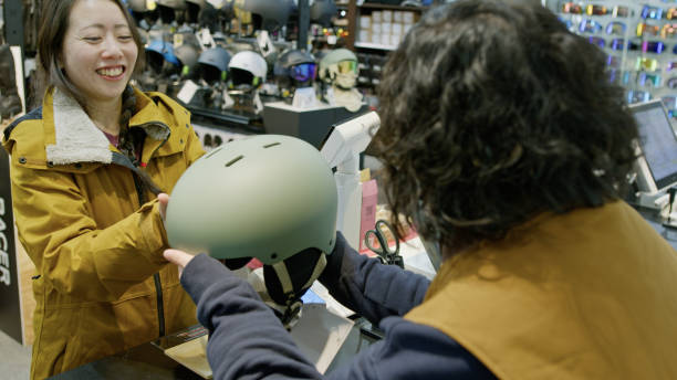 Japanese woman buying a helmet in a ski and snowboard equipment store at the lodge at the base of the mountain in Niseko.