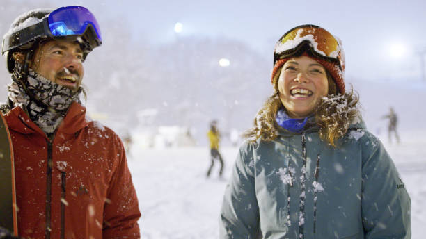 A group of skiers and snowboarders chatting and joking around at the base of the mountain in Niseko, preparing for a session of night skiing.