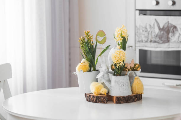 istock Happy Easter. Spring yellow hyacinth flowers in an egg-shaped vase, chicken chicks on a white table. In the background is a white Scandinavian-style kitchen. Easter decor in the house. 2103418653
