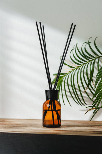 istock Aromatic Reed Diffuser on Wooden Table With Vibrant Green Leaves Against White Background 2103438723