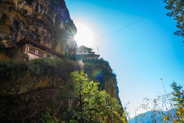 Low angle view of Tigers Nest Monastery with the sun shinning right behind it from the mountains edge
