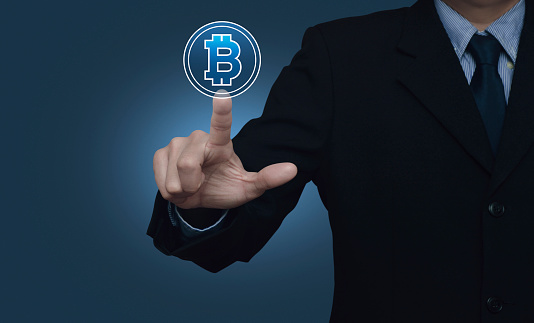 Businessman pressing bitcoin icon over light blue wall, Choosing bitcoin concept