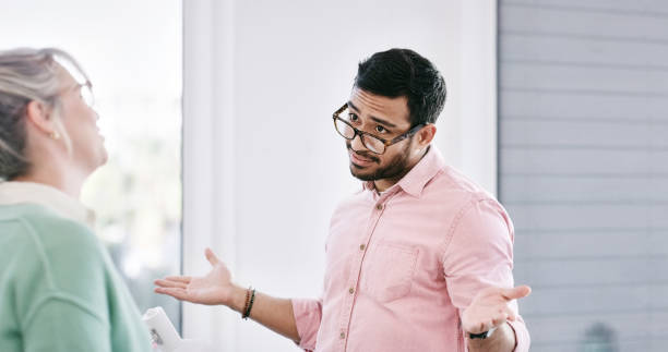 istock Coworker, office and discuss with shrug for confused or doubt with project, work and  knowledge. Colleagues, diverse group and conversation with arms open for answer, question and unsure at workplace 2103447508