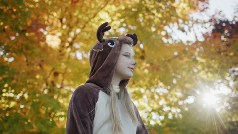 Happyl child in deer costume dancing near autumn tree