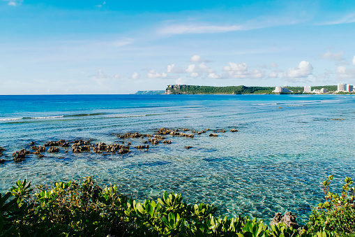 A scenic view of fluffy white clouds over sandy Tumon Beach, Guam, USA