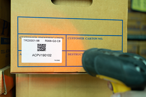 Close-up, wireless barcode reader, reads information from a QR code on the carton.