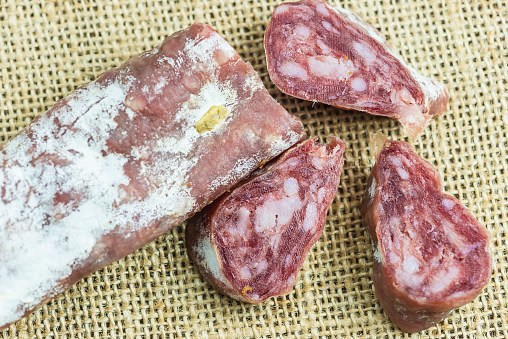 Slices of salami or saucisson on a burlap background
