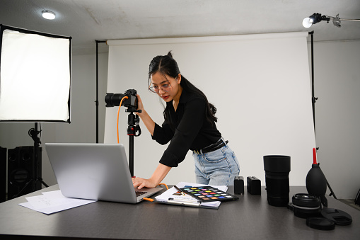 Portrait of female photographer with professional camera working in modern studio.