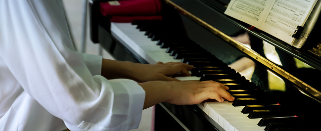 Close-up of pianist hand playing piano, player practice music according to the song's key.