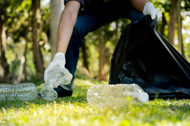 istock Hand holding plastic bottle waste, picking up trash and putting it in the black garbage bag at the Park on Environmental Earth day 2103620852