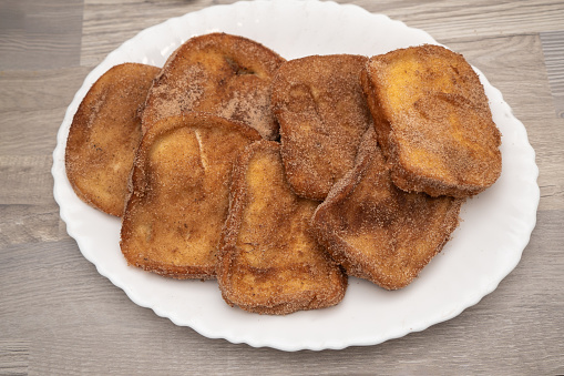 A plate full of sugared torrijas, a traditional Spanish dessert, ready to be served.