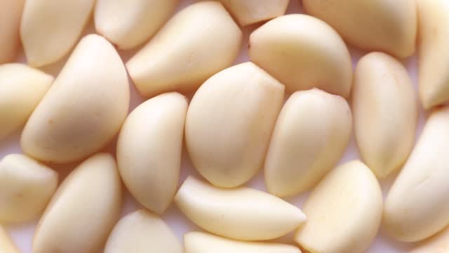 Top view of fresh whole white garlic cloves circle rotation close up