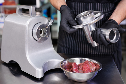 The cook assembles a electric meat grinder before cooking minced meat
