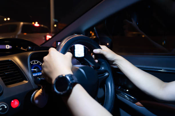 istock Male hands holding the steering wheel while driving a car at night 2103699070