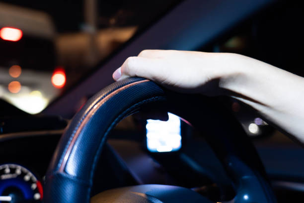 istock Male hands holding the steering wheel while driving a car at night 2103699071