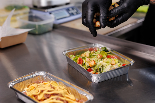 The chef prepares the food in the restaurant and packs it into disposable lunch boxes