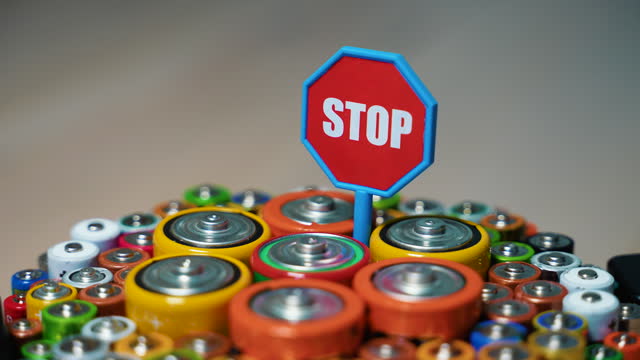 Stop pollution by batteries. Old used batteries type AA, AAA, D and stop sign rotate in a circle