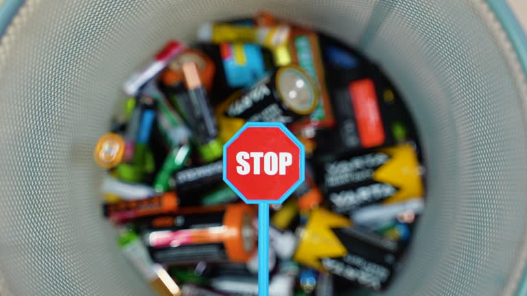 A person throws used batteries into office garbage bin. Stop pollution by batteries