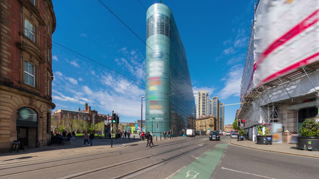 Road traffic and pedestrians with blue sky and moving clouds in the city centre of Manchester, England - 4k time lapse (tilt up)