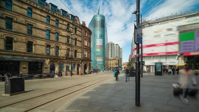 Road traffic and pedestrians with blue sky and moving clouds in the city centre of Manchester, England - 4k time lapse