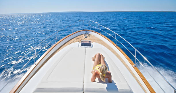 istock Woman sunbathing on deck of yacht 2103810545