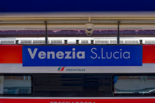 Blue and white sign at platform of railway station of Venice Santa Lucia on a sunny summer day. Photo taken August 11th, 2023, Venice, Italy.