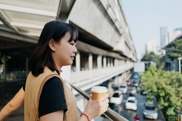 istock Asian woman having coffee on the go 2103830152