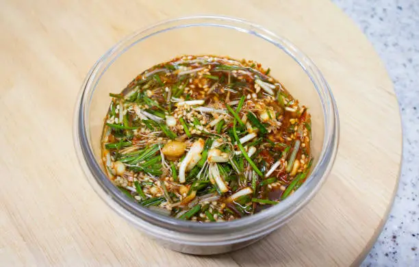 Wild Chive seasoning sauce  in a glass bowl on a wooden tray. This seasoning sauce made with soy sauce base and wild chive as the main ingredient, which Koreans enjoy eating in spring.