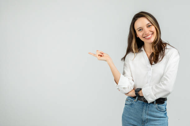 istock A friendly young woman with a radiant smile points to the side 2103842480
