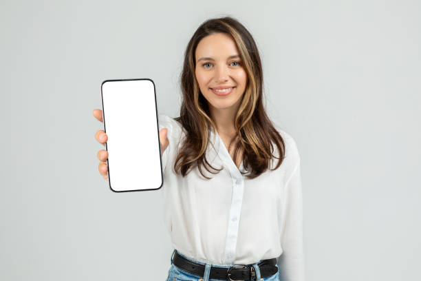 istock Confident young female with a friendly smile showcasing a smartphone 2103842497