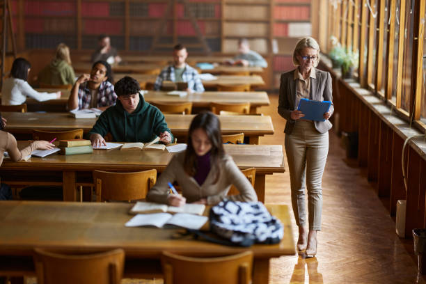 istock Senior female professor reading paperwork on the move in library. 2103847703