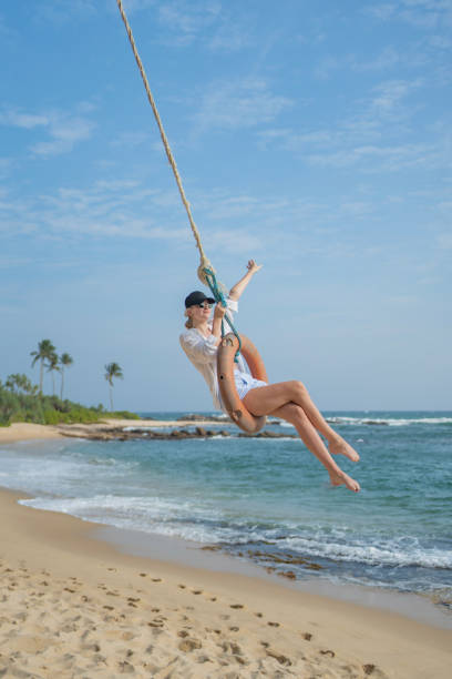istock Young woman swings over beach 2103860170