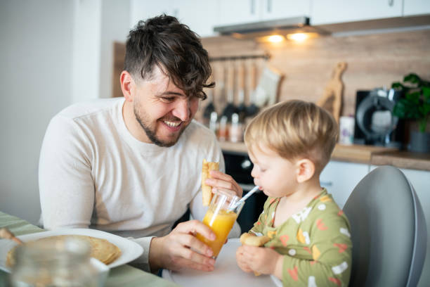 istock Father and toddler son having breakfast at kitchen table. 2103861773